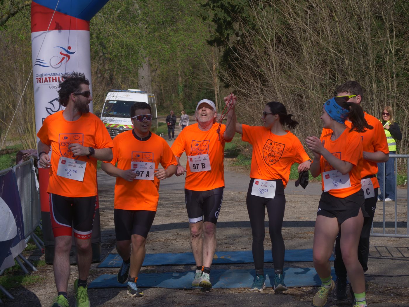 L'équipe A2CMieux franchissant l'arche d'arrivée d'une course, bras levés.