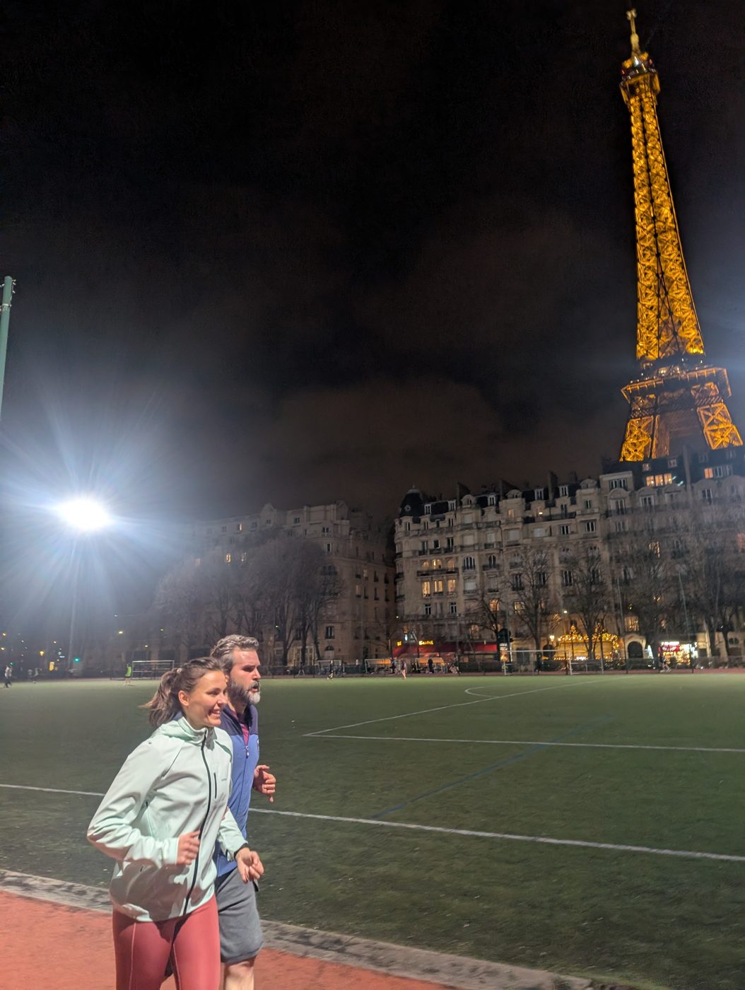 Deux coureuses A2CMieux devant la tour Eiffel illuminée en soirée.