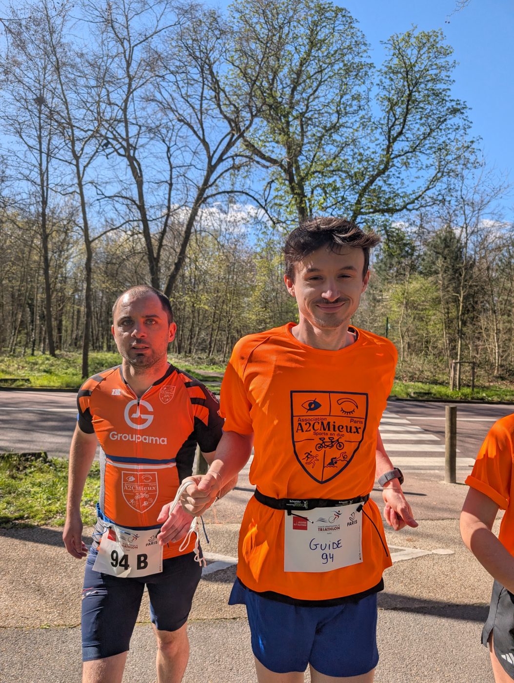 Un duo de coureurs A2CMieux souriants, paysage de nature en arrière-plan.