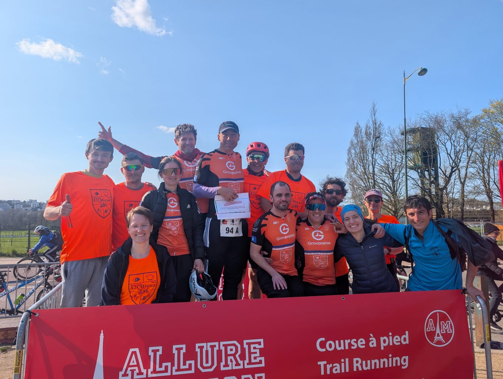 L'équipe A2CMieux réunie et souriante derrière une banderole de course, après une épreuve de duathlon.